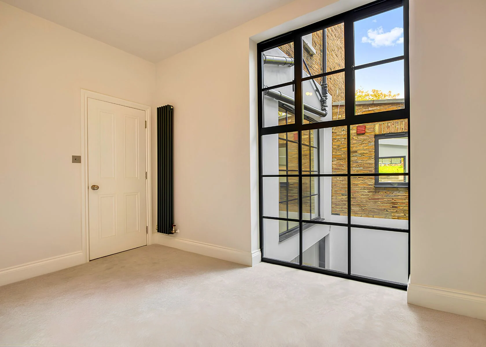 Fernhurst Road: A room with a full-height, black-framed glazed opening.